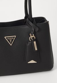 Sort faux læder håndtaske med en struktureret form, udstyret med gyldent hardware, et trekantet logo og et vedhæftet tag.