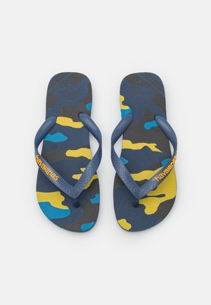 Chanclas de camuflaje azul y amarillo con suelas de goma texturizadas y correas de color azul oscuro que presentan el logo de "Havaianas" en naranja.