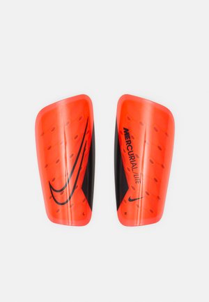 Espinilleras Nike Mercurial Lite en naranja brillante con acentos negros, que presentan una textura elevada, un diseño aerodinámico y indicadores "L" y "R".
