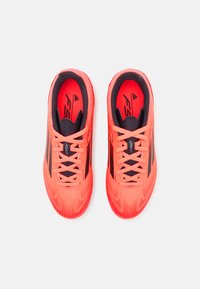 Zapatillas deportivas de color rojo brillante con una superficie texturada y estriada. Accentos negros en los lados y los cordones; cuello acolchado para mayor comodidad.