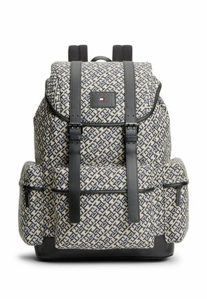Rucksack mit beigem und dunkelblauem geometrischem Muster, Front- und Seitentaschen, schwarzen Lederträgern mit Schnallen und einem Logo-Patch auf der Klappe.