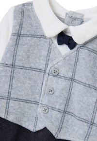 Completo a quadretti grigi e bianchi con design con colletto, texture morbida, tre bottoni grigi e un fiocco blu navy come dettaglio.