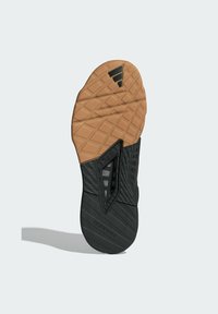 Black and gum rubber outsole with textured patterns and grooves for traction; features a flexible, contoured design with distinctive accents.