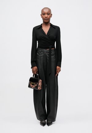 Blusa negra de mangas largas, pantalones de cuero negros de cintura alta y un bolso pequeño con estampado de leopardo y acentos en negro.