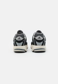 Svarte og grå Adidas-sneakers har en overdel i mesh og semsket skinn, tykk hvit mellomsåle og en gummisåle med et teksturert mønster.