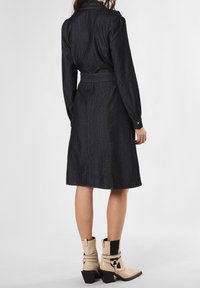 Dunkelblauses Denim-Shirtkleid mit langen Ärmeln, tailliertem Gürtel und geknöpften Manschetten, das einen knielangen A-Linien-Schnitt und eine glatte Textur aufweist.