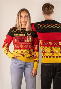 Strickpullover in den Farben Rot, Gelb und Schwarz. Er verfügt über festliche Muster, darunter Hunde, Bierkrüge, Brezeln und Nussknackerfiguren.