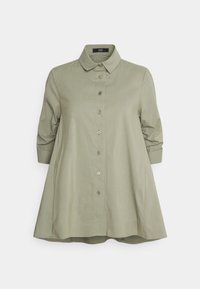 Camicia verde oliva chiaro realizzata in tessuto liscio, con colletto, chiusura a bottoni e maniche a tre quarti con polsini arrotolati.