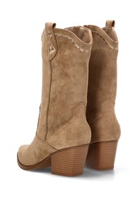 Botas de ante en color marrón claro hasta el tobillo con un tacón cuadrado, que presentan detalles de costura a lo largo de los bordes y un diseño de punta afilada. Tacón texturizado para mayor agarre.