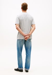 Γκρι βαμβακερό μπλουζάκι, άνετη γραμμή, συνδυασμένο με ανοιχτό μπλε τζιν παντελόνι. Το τζιν έχει κλασικό σχέδιο με πέντε τσέπες και ελαφρώς ξεφτισμένα τελειώματα.