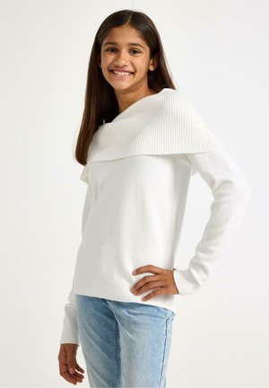 Weißer Pullover mit geripptem, schulterfreiem Ausschnitt und langen Ärmeln, kombiniert mit hellblauen Jeans. Weiche Textur, lockere Passform.