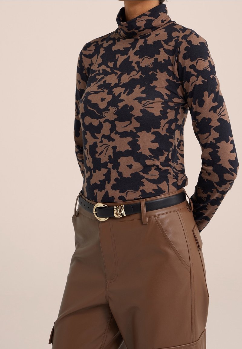 Dlouhý rukáv rolák v hnědo-námořnickém květinovém vzoru, kombinovaný s hnědými koženými kalhotami a černým opaskem se zlatou sponou.