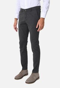 Pantaloni chino grigi in cotone con vestibilità dritta, chiusura a bottone, tasche frontali e abbinati a stivaletti in camoscio grigio chiaro.