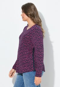 Navy pitkähihainen toppi, jossa on vaaleanpunaisia kalakuvioita, V-pääntie ja sivuhaalareita. Yhdistettyinä sinisiin farkkuihin. Suuri kangaslujuus.