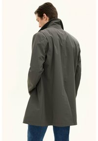 Grå vattentät kappa med hög krage och avslappnad passform, med långa ärmar och en slät, matt finish. Bakvy.