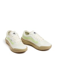 Vans sneakers featuring a cream canvas upper with a mint green side stripe and a textured beige rubber sole. Laced design with padded collar.
