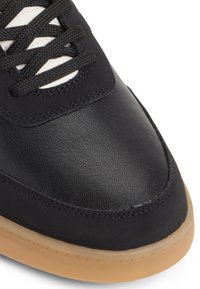 Sneaker nera con tomaia in pelle testurizzata, punta rotonda, design con lacci e suola in gomma. Presenta dettagli cuciti e occhielli a contrasto.