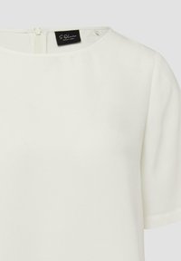 Blouse blanche à manches courtes avec encolure arrondie et fermeture éclair au dos, dotée d'une étiquette noire portant le nom de la marque "S. Oliver Black Label".