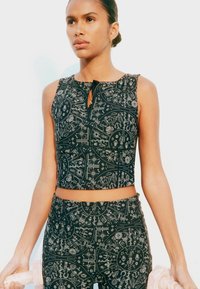 Zwart cropped top met complexe zilveren patronen, voorzien van een keyhole neklijn en een gladde textuur, gecombineerd met bijpassende onderkleding.