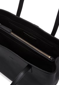 Svart läder toteväska med ett dragkedjefack, inre fickor för att smidigt förvara saker och en mjuk yta med hållbara handtag. Minimalistisk design.