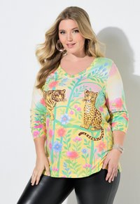 Bluzka z długim rękawem i dekoltem w serek w kolorowy, kwiatowy wzór z motywem tygrysa i lamparta, utrzymana w pastelowych odcieniach żółci, zieleni i różu.