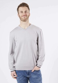 Pull over gris clair en v à manches longues, en tissu tricoté texturé, avec un ourlet et des poignets côtelés à bord foncé, associé à un jean bleu.