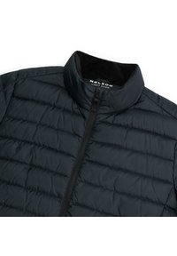 Donkerblauwe lichtgewicht donsjas met gequiltde textuur, hoge kraag en ritssluiting aan de voorkant. Het interieur heeft een zachte zwarte voering.