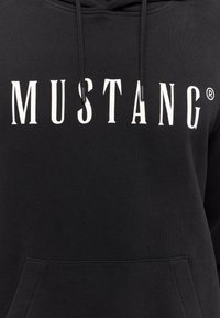 Felpa nera con un grande logo bianco "MUSTANG". Include una tasca frontale e coulisse regolabili. Tessuto morbido e texture piacevole.