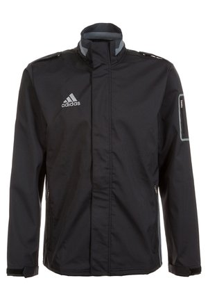 Schwarze Adidas-Jacke mit hohem Kragen, Reißverschlusstasche auf der Brust und Logo auf der linken Brust, mit reflektierendem Besatz an der Tasche des linken Ärmels.
