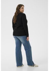 Pulover negru tricotat cu mâneci lungi, asociat cu blugi evazați de culoare albastru deschis și adidași alb-negru. Design simplu, ajustat, fără modele.
