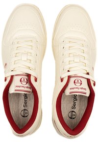 Pár krémových tenisiek Sergio Tacchini s červenou vnútornou podšívkou a bielymi šnúrkami, pohľad zhora na bielom pozadí.