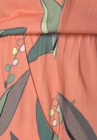 Tissu à motif floral dans des tons pêche, avec des détails verts et jaunes. Texture douce avec un design plissé et un léger éclat.