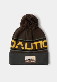 Brązowa dziana czapka z pomponem, z wyraźną fakturą na górze, z żółtymi i zielonymi paskami. Zawiera prostokątną naszywkę z motywem gór i słońca.