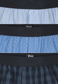 Tre paia di boxer con elastico in vita blu navy. In alto: tessuto a righe azzurre. Al centro: blu con pois bianchi. In basso: motivo a quadretti blu navy.