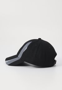 Casquette noire avec une visière incurvée et des accents de rayures grises sur le côté. Fabriquée en tissu avec une surface texturée et une sangle ajustable à l'arrière.