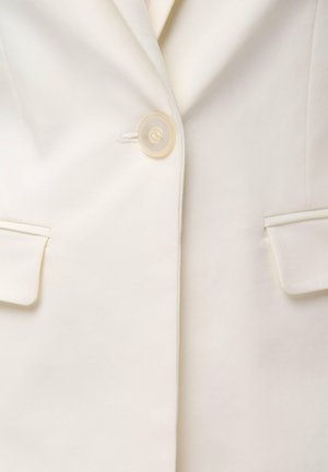 Cream blazer with a single button closure, notched lapels, and two front pockets, featuring smooth fabric and subtle stitching details.