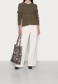 Cardigan en maille vert olive avec des rayures texturées, fermeture à boutons, associé à un pantalon large crème et un sac fourre-tout léopard noir et beige.
