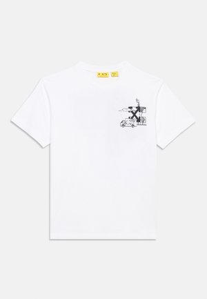 T-shirt bianca a maniche corte con una piccola grafica nera sul petto che mostra un camion accanto a edifici da cui sale del fumo.