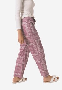 Pantaloni rosa a fantasia presentano un motivo floreale con dettagli a bordura. Realizzati in tessuto leggero, hanno una vestibilità ampia con gamba dritta e vita con coulisse.