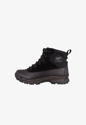 Musta vaelluskengät, joissa on teksturoitu nyloni päällinen, nauhakiinnitys, kuminen varvaskuppi ja kestävä pohja, joka antaa hyvää pitoa. Sorel-logo sivussa.