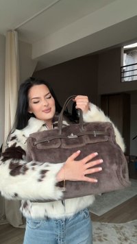 Brun faux fur håndtaske med to håndtag, frontlomme og detaljer i sølv hardware. Den bløde tekstur komplementerer den slanke silhuet.