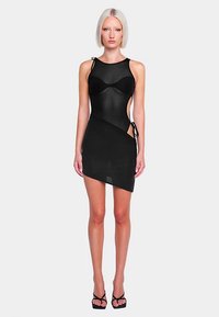 Schwarzes Mini-Kleid aus transparentem Stoff, figurbetonte Form und seitliche Bindungen. Verfügt über einen runden Ausschnitt und einen Saum bis zur Mitte des Oberschenkels. Modell trägt hohe Absätze.