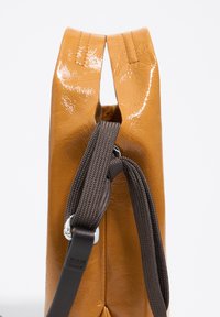 Brązowa, błyszcząca torebka typu handbag o sztywnym fasonie, z gładką teksturą i dwukolorowymi paskami. Dodatki to metalowe elementy wykończenia.