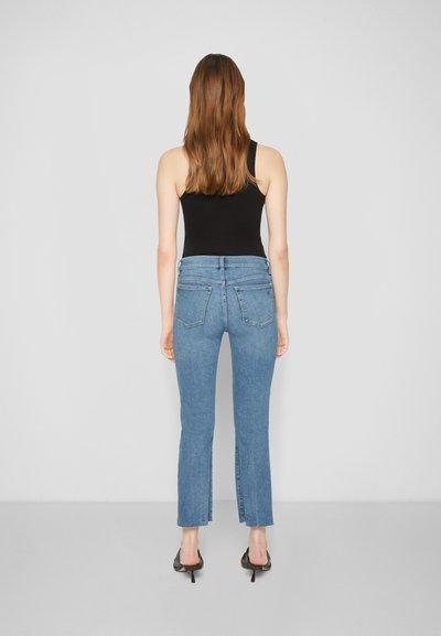Jeans de ganga azuis de cintura alta com um corte flare, apresentando bolsos traseiros e fendas laterais nas bainhas. Textura suave com um design casual.