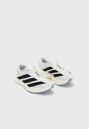 White athletic shoes with black stripes and branding, featuring a mesh upper, rounded toe, and thick cream sole for cushioning.