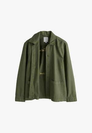 Oliivinvihreä nappikiinnitteinen puuvillatakki, jossa kaksi etutaskua, kauluksellinen pääntie ja hillitty tekstidetalji sisäpuolella.