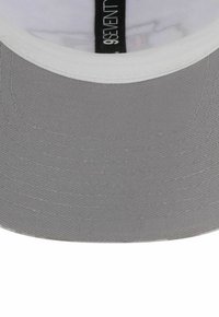 Graue Baseballmütze mit einem flachen Schirm, aus strukturiertem Stoff, mit einem weißen Unterkühl und einem schwarzen Etikett im Inneren.