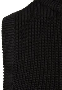 Svart stickad tröja med ribbad textur och hög krage. Tyget visar detaljerad sömnad och en åtsittande design.