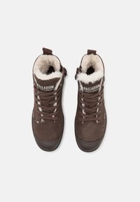 Bottines hautes marron en daim avec une douce doublure en fourrure blanche, conception à lacets et embout renforcé en caoutchouc. Présente un logo sur la languette.