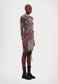 Robe à manches longues en tissu transparent avec un motif floral, présentant des nuances de rose, de violet et de bleu. Comprend des détails à cordon de serrage à l'ourlet.